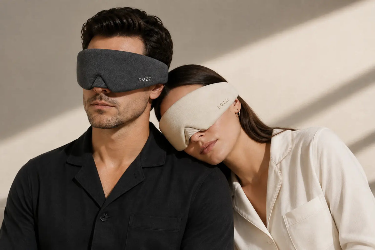 A couple wearing DOZZI masks in Black and Apricot, resting together in warm light