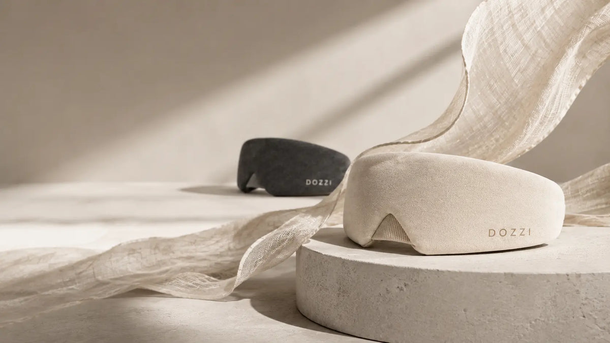 Apricot and Black DOZZI masks on a warm surface beside flowing fabric